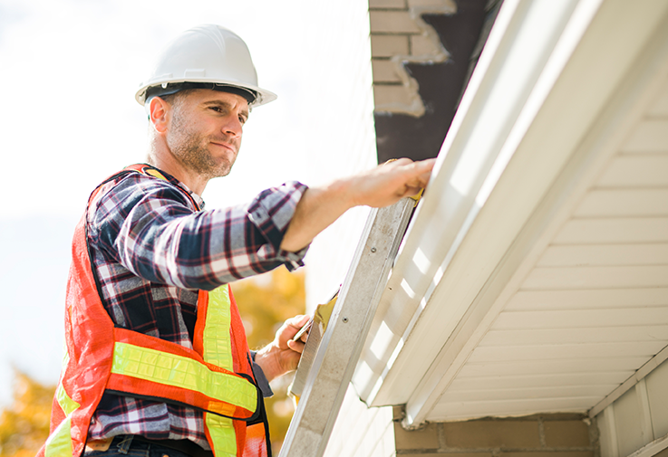 Roofer inspecting house roofline